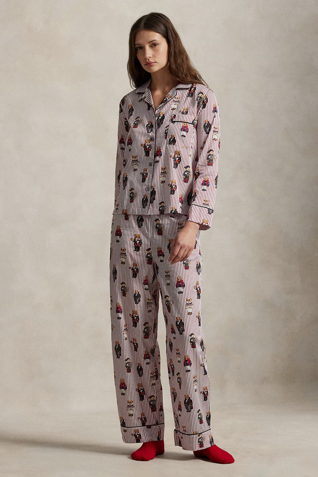 Woman wearing a patterned pajama set with red socks on a neutral background