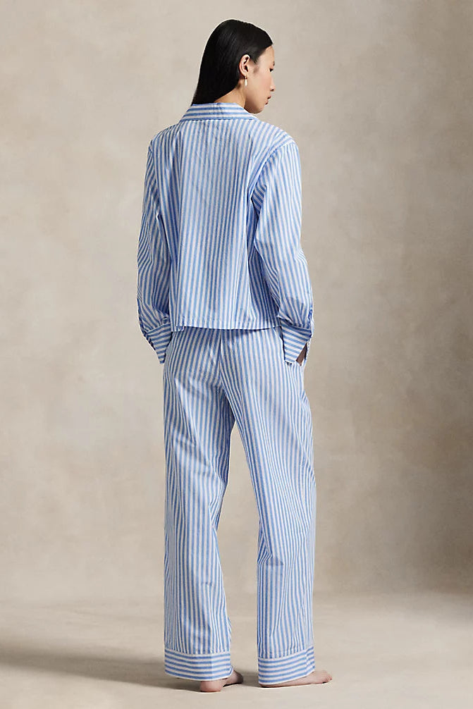 Person wearing a blue and white striped pajama set against a beige background