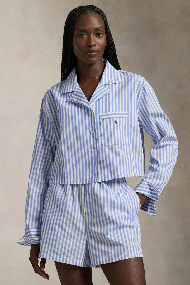 Woman wearing a blue and white striped pajama set against a beige background