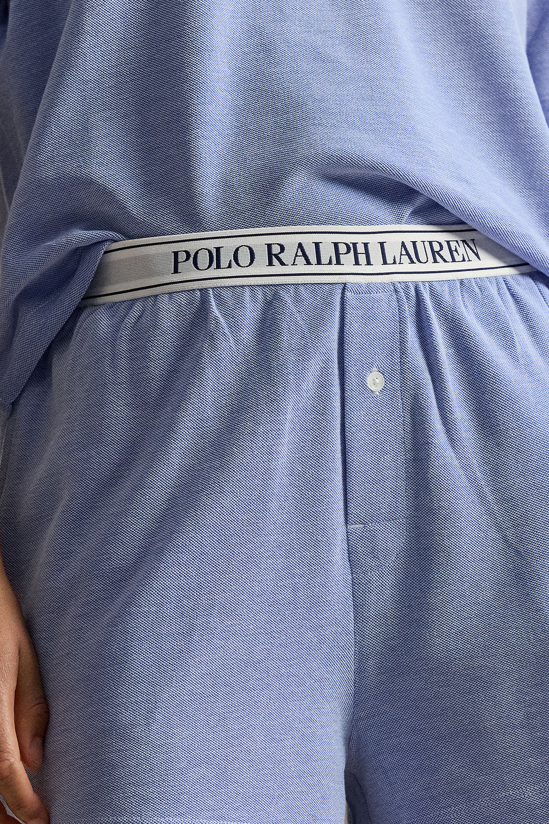 Close-up of a person wearing light blue Polo Ralph Lauren lounge shorts, showing the branded elastic waistband and part of the matching top.