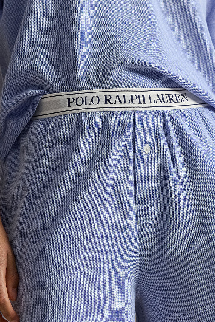 Close-up of a person wearing light blue Polo Ralph Lauren lounge shorts, showing the branded elastic waistband and part of the matching top.