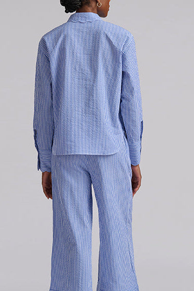 Person wearing a blue striped pajama set on a gray background