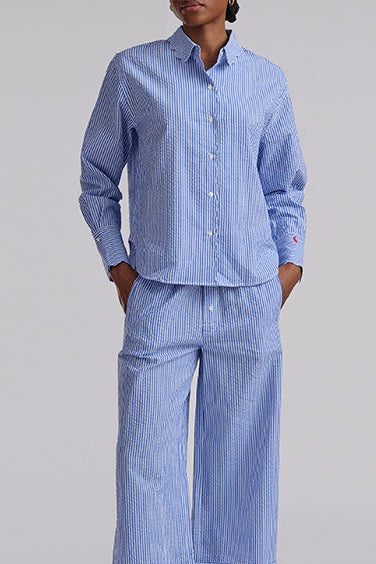 Person wearing a blue striped pajama set on a gray background