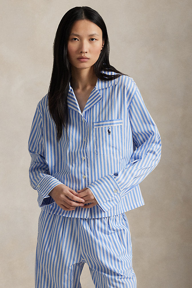Woman wearing blue and white striped pajamas against a beige background
