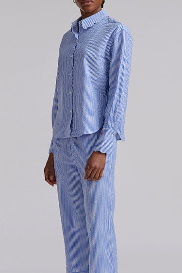 Person wearing a blue striped seersucker pajama set on a gray background