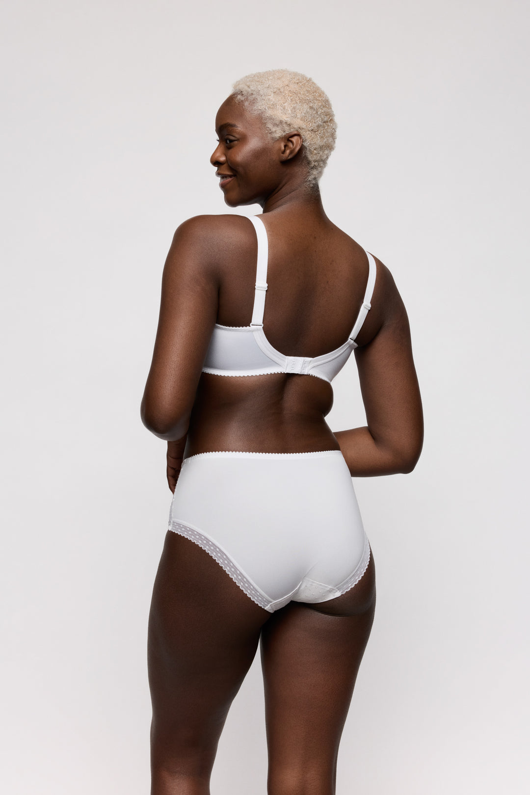 Woman wearing a white bra and panties set on a light gray background. Full coverage everyday high briefs.