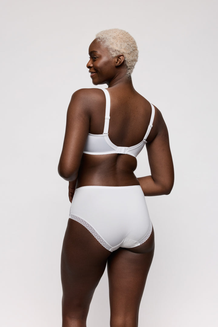 Woman wearing a white bra and panties set on a light gray background. Full coverage everyday high briefs.