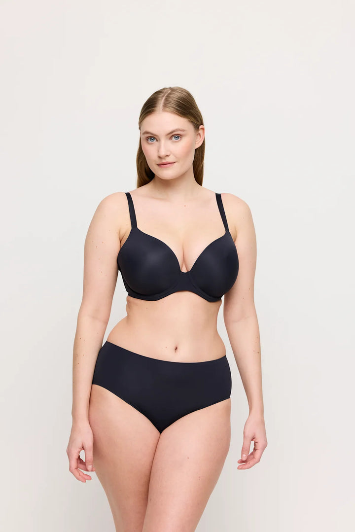 Woman wearing a black bra and high-waisted underwear on a light gray background