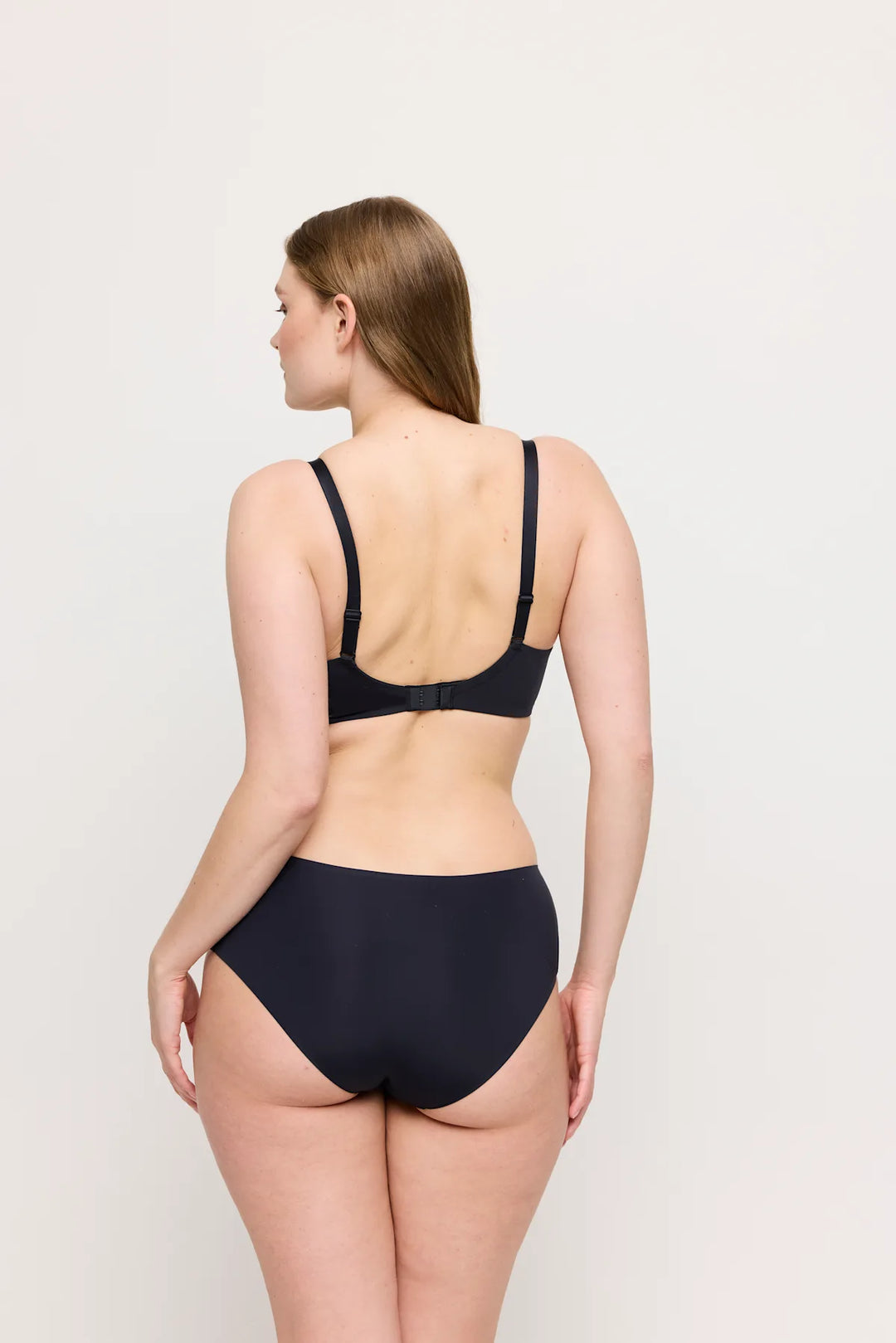 Woman wearing a black bikini set on a plain background