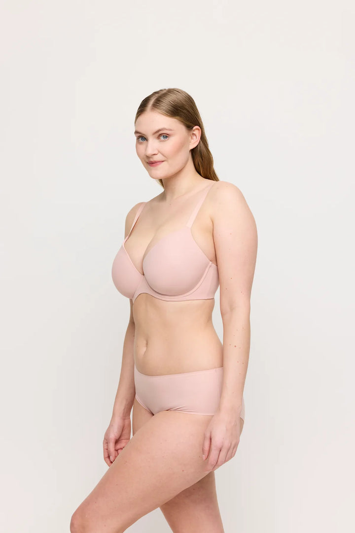 Woman wearing a light pink bra and underwear set on a white background