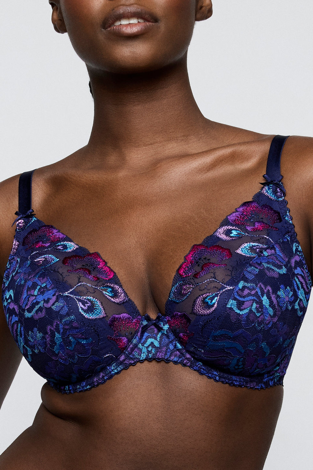 Woman wearing a floral lace bra on a plain background