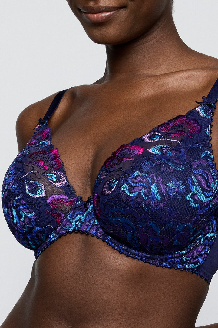 Woman wearing a blue floral lace bra against a gray background