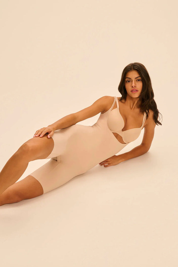 Woman wearing a beige shapewear garment on a plain background