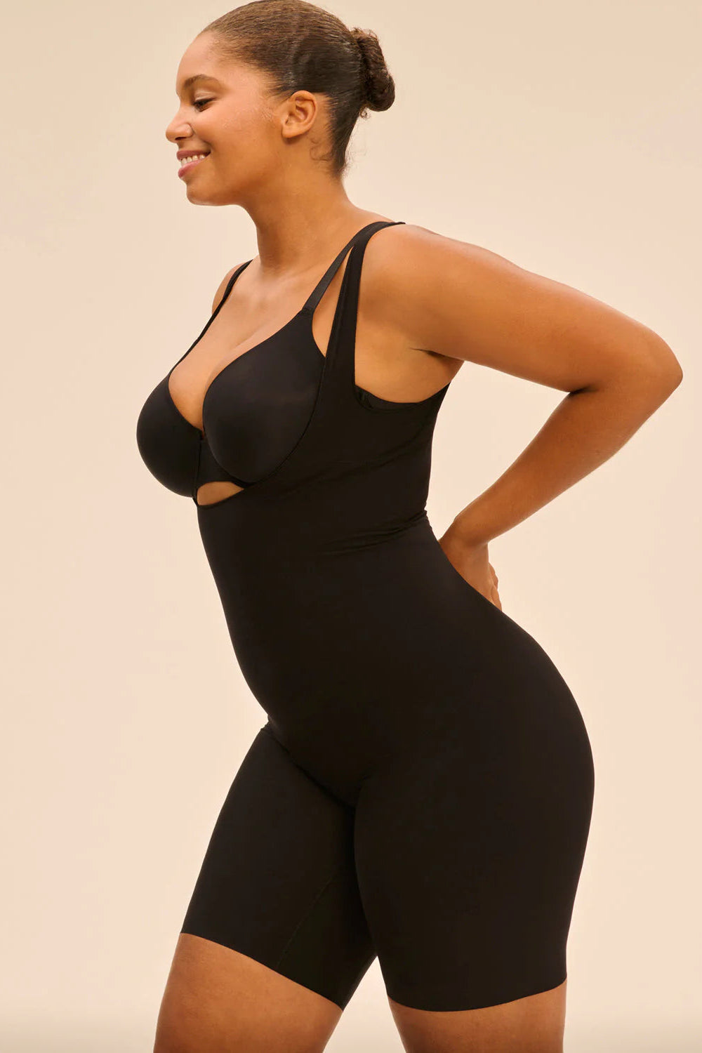 Woman wearing a black bodysuit against a beige background