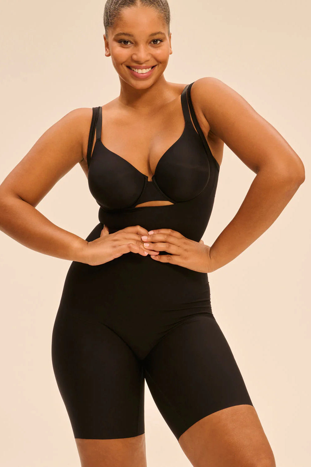 Woman wearing a black shapewear outfit on a beige background