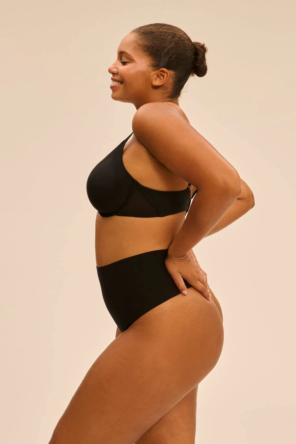 Woman wearing a black lingerie set against a beige background