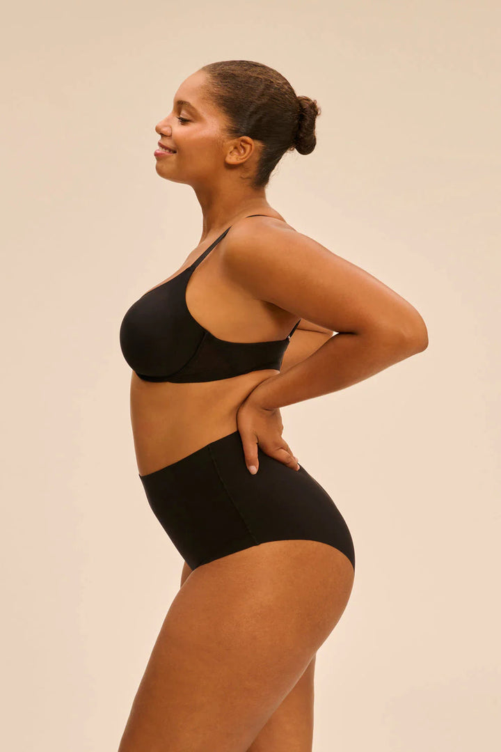 Woman wearing a black lingerie set against a beige background