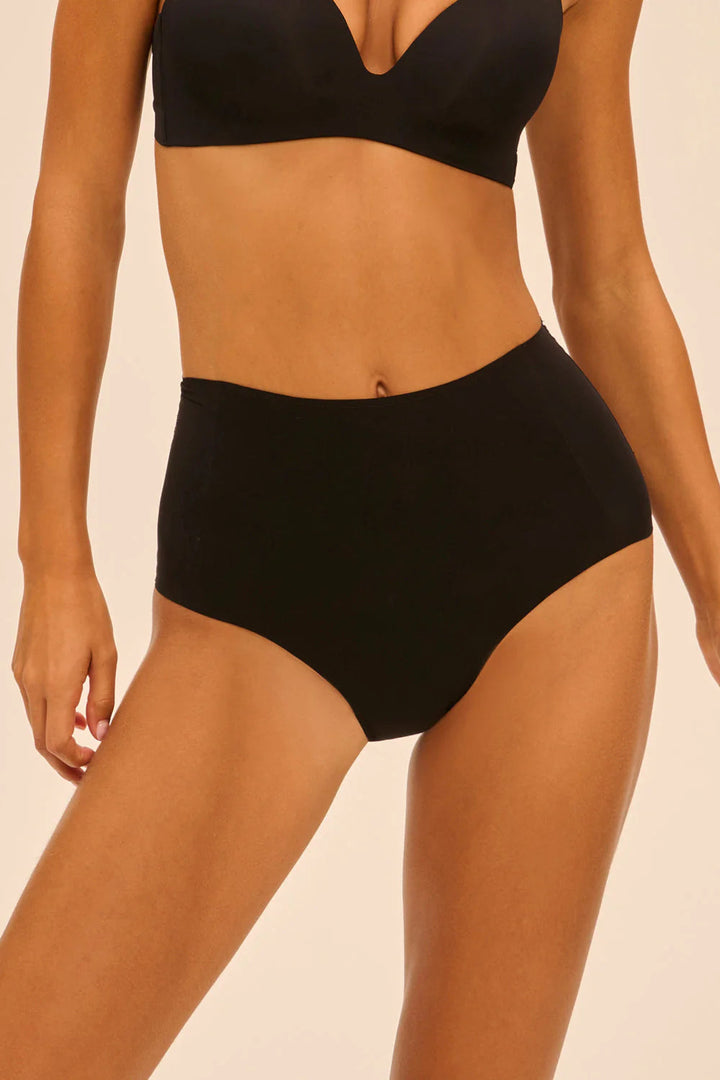 Person wearing a black lingerie set on a beige background