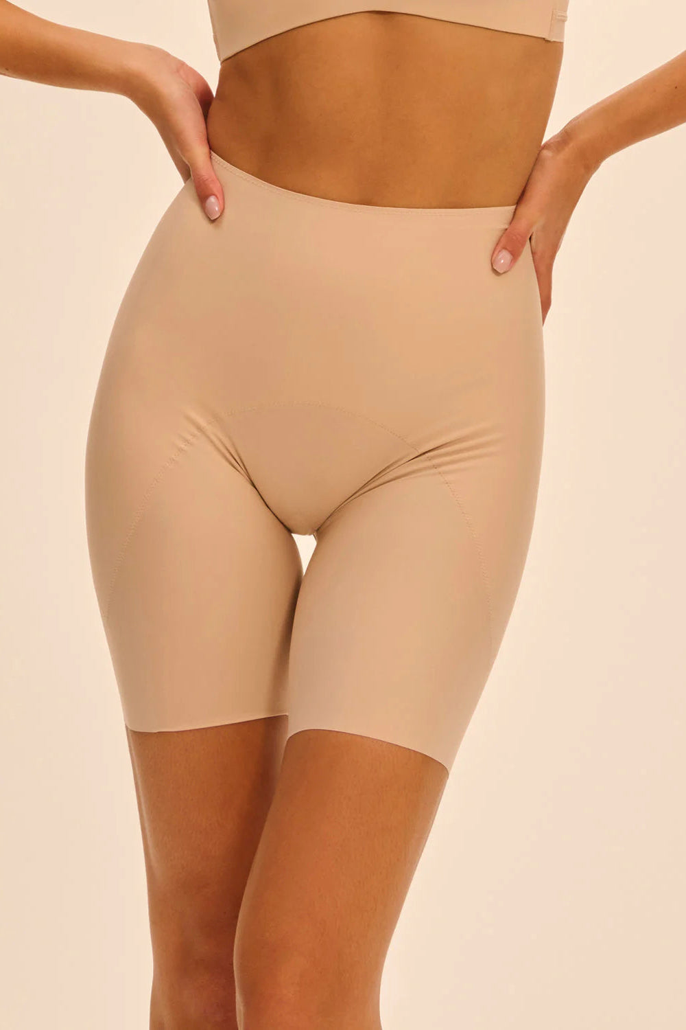 Beige shapewear shorts worn by a person on a beige background