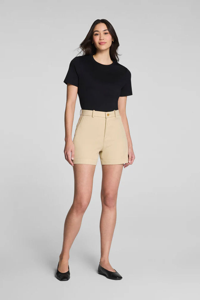 Woman wearing a black t-shirt and beige shorts on a gray background
