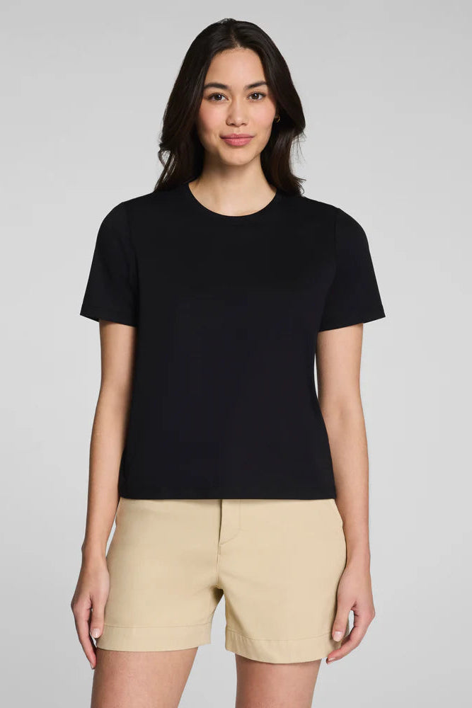 Woman wearing a black t-shirt and beige shorts on a gray background