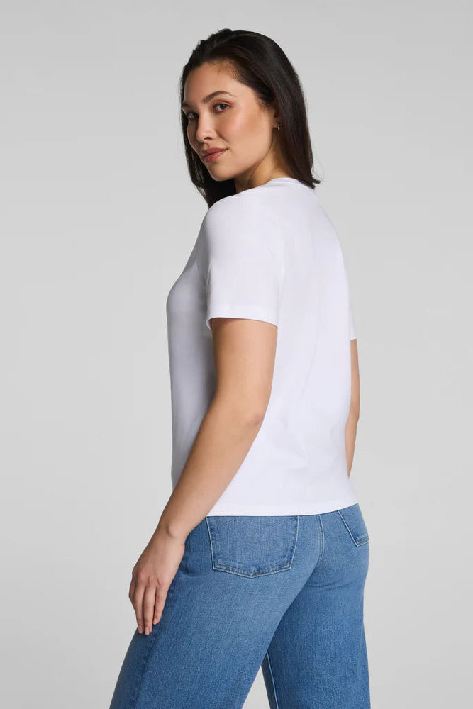 Woman wearing a plain white t-shirt and blue jeans on a light gray background