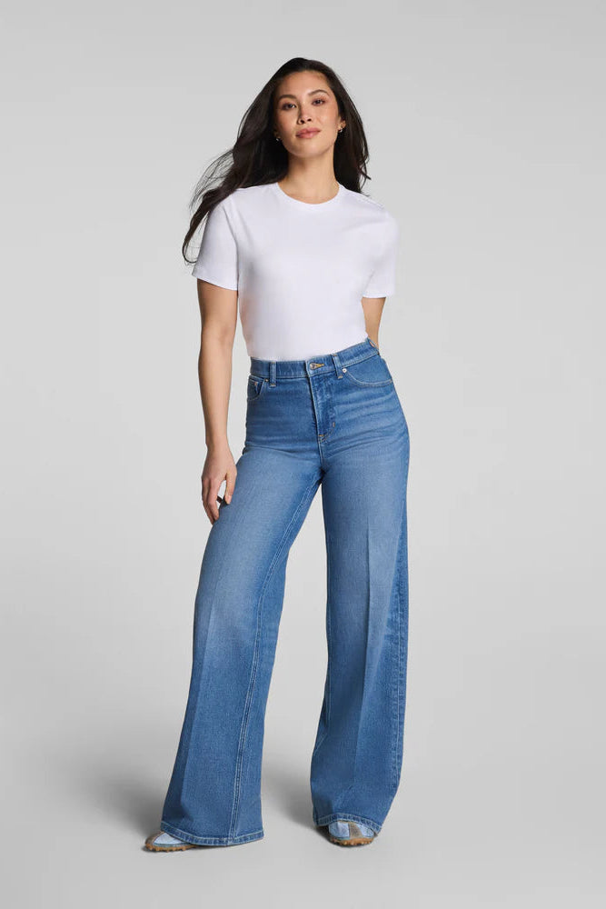 Woman wearing a white t-shirt and blue jeans on a gray background
