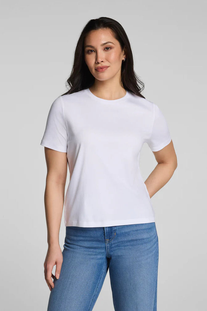 Woman wearing a plain white t-shirt and blue jeans on a light gray background