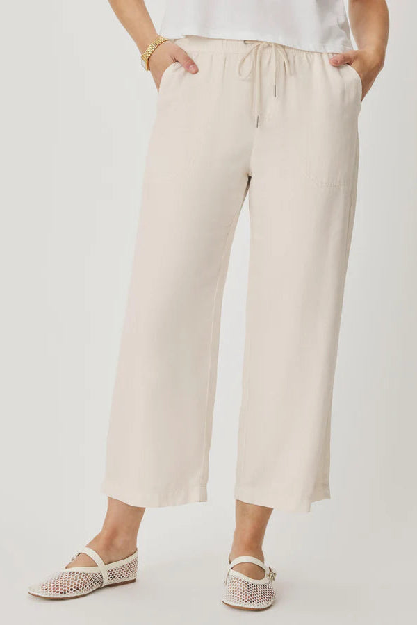 Person wearing beige wide-leg pants on a white background