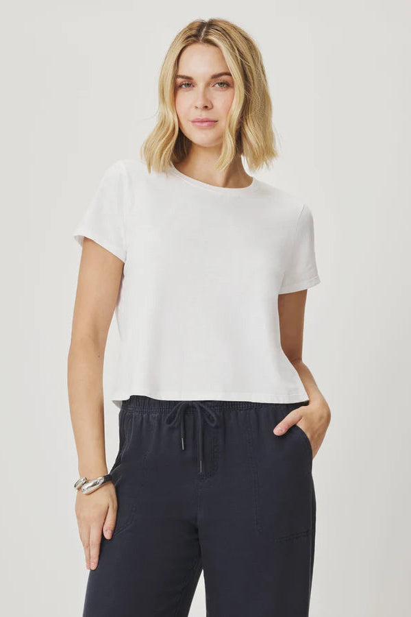 Woman wearing a white t-shirt and navy pants on a plain background