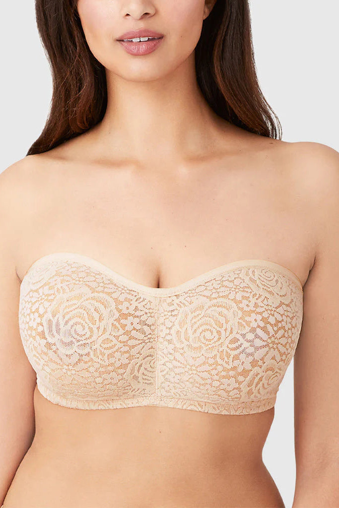 Woman wearing a beige lace strapless bra against a plain background